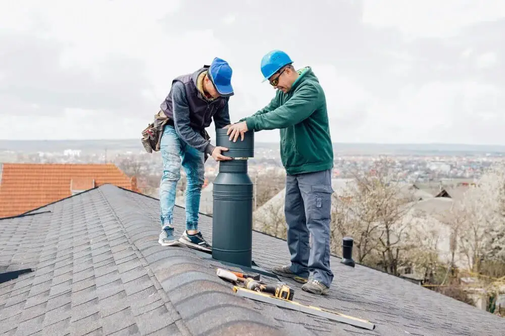 Chimney installation on roof by Workers